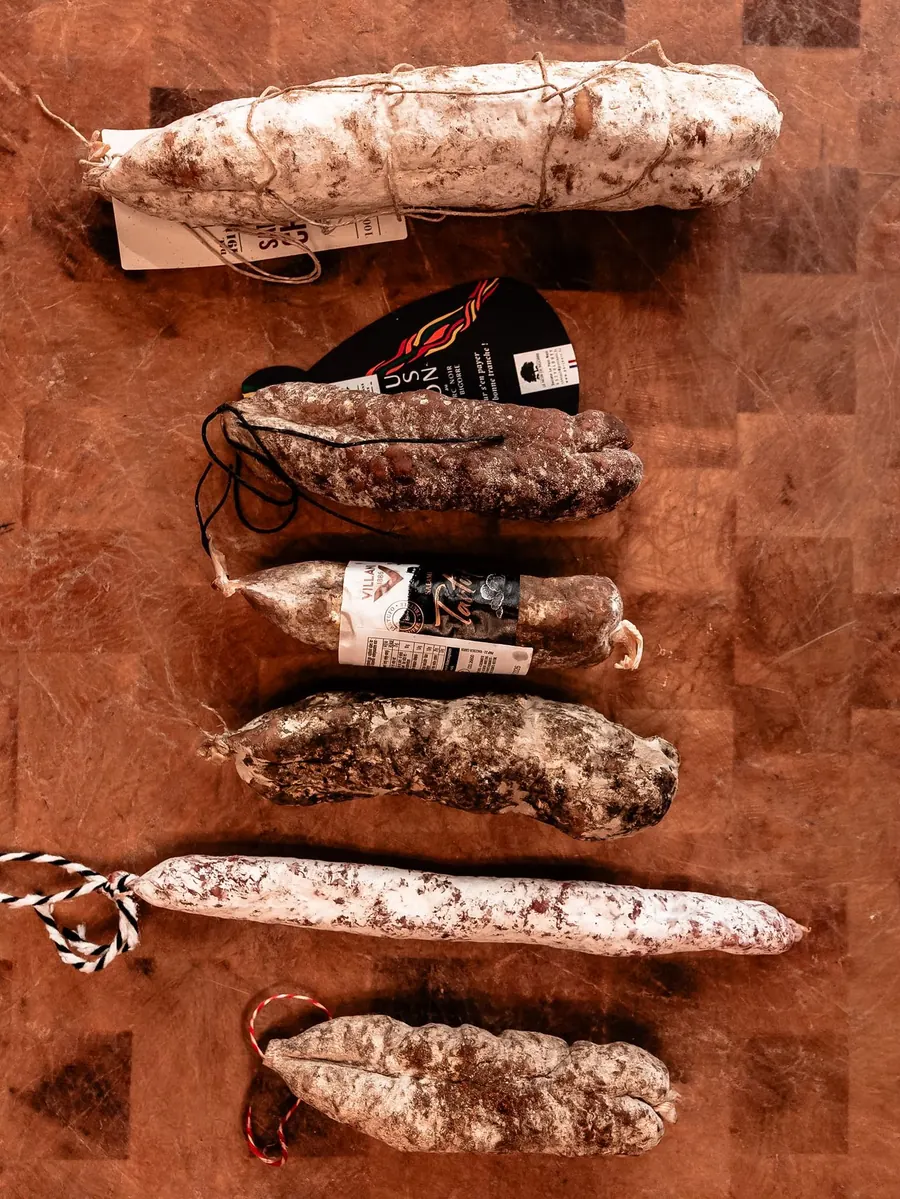Six saucissons secs alignés sur un billot